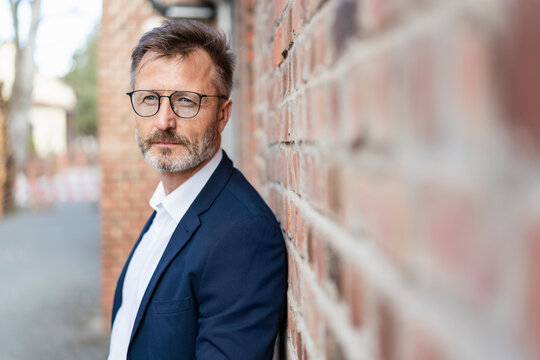 Portrait of businessman at brick wall looking sideways