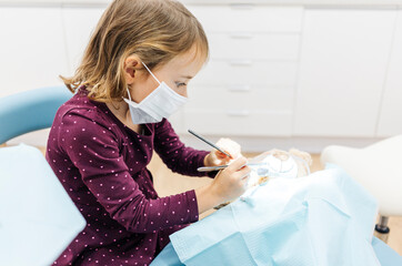 Girl at the dentist examining teddy bear