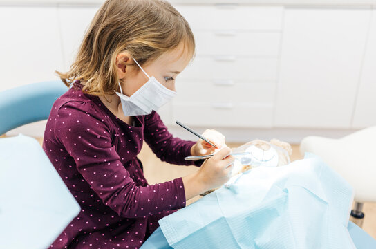 Girl at the dentist examining teddy bear