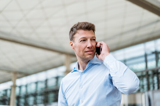 Businessman Outside In The City On Cell Phone Looking Around