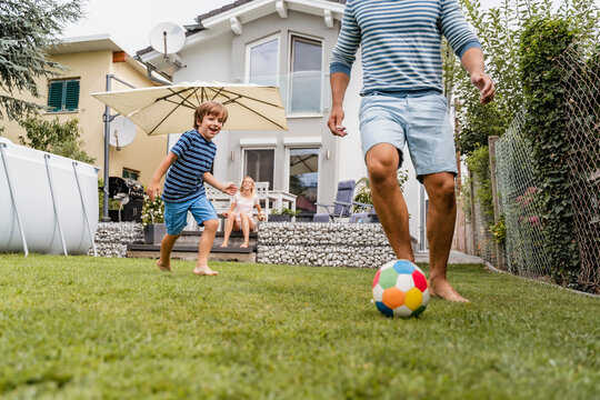 Father and son playing football in garden