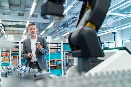 Businessman examining workpieces in a modern factory hall