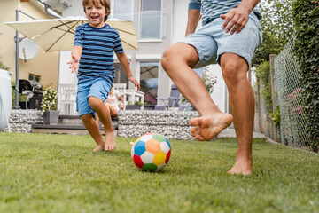 Father and son playing football in garden