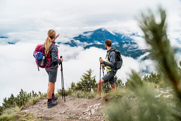 Young couple on a hiking trip in the mountains looking at view, Herzogstand, Bavaria, Germany