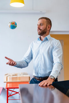 Businessman throwing up miniature globe in office