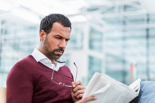 Businessman reading a newspaper in waiting hall