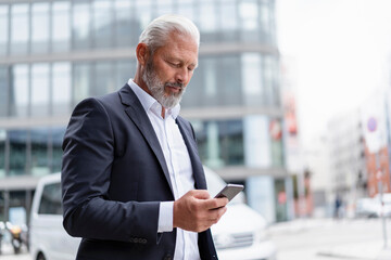 Mature businessman using cell phone in the city