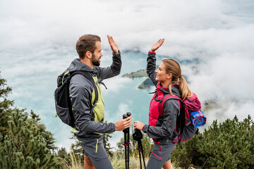 Happy young couple on a hiking trip in the mountains high fiving, Herzogstand, Bavaria, Germany