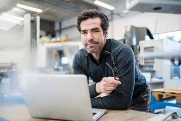 Portrait of businessman using laptop in a factory
