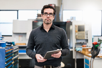 Portrait of a businessman holding tablet in a factory