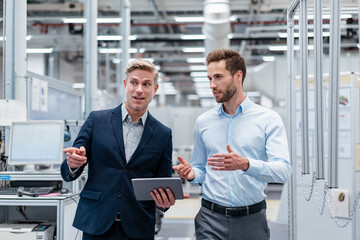 Two businessmen with tablet talking in a modern factory