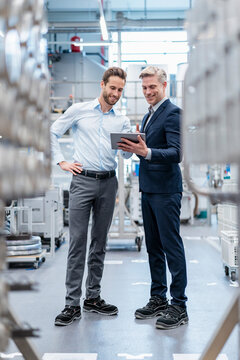 Two businessmen with tablet talking in a modern factory
