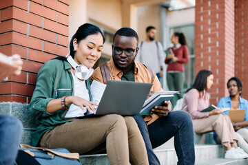 Young multiracial students use laptop while learning at campus.