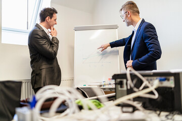 Two businessmen in office discussing at flip chart