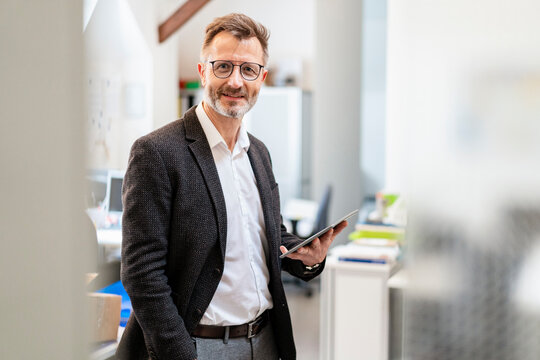 Portrait of smiling businessman using tablet in office