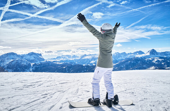 Mature woman with snowboard on ski slope with raised arms