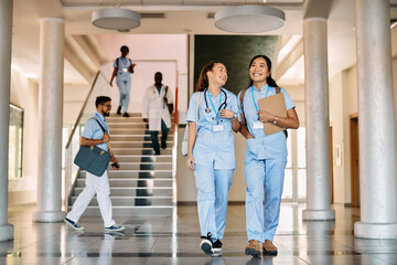 Happy female medical students walk through hallway at medical university.