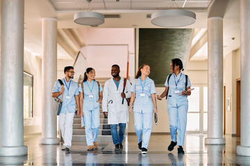 Multi-ethnic group of happy medical students walk through hallway at medical university.