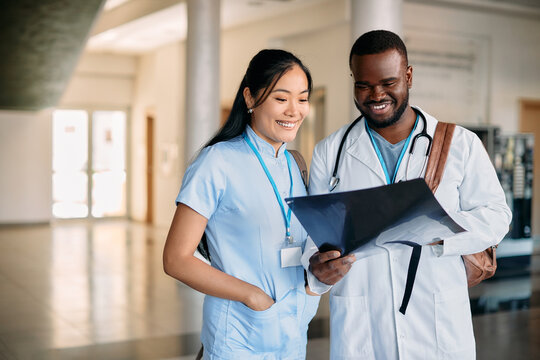 Happy multiracial medical students examine X-ray image while having internship at university hospital.