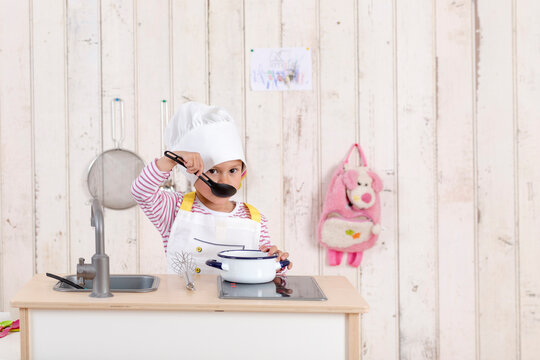 Portrait of little girl playing with toy kitchen