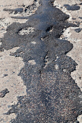 a bad asphalt road that has been repaired many times