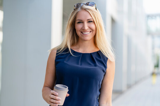 Portrait of smiling blond businesswoman with coffee to go in summer