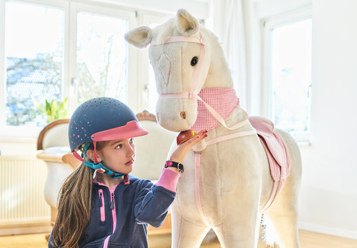 Girl feeding her toy horse at home