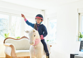 Girl riding on play horse at home