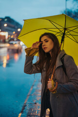 Woman holding a yellow umbrella while waiting for a cab