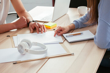 Close-up of colleagues working together at desk in office discussing papers