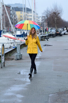 Denmark, Copenhagen, happy woman with colourful umbrella strolling at city harbour