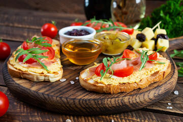 Grilled bruschetta with chicken rillettes, jamon and herbs. Delicious toast with chicken pate and different appetizers