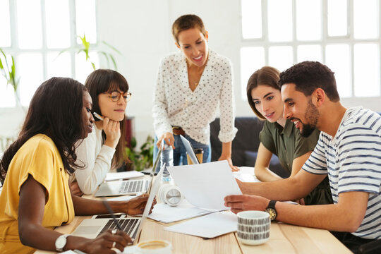 Smiling colleagues working together at desk in office