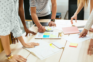 Close-up of colleagues working together at desk in office discussing papers