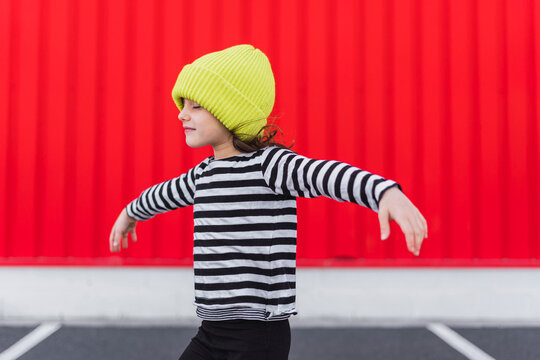 Little girl wearing striped shirt and yellow cap balancing