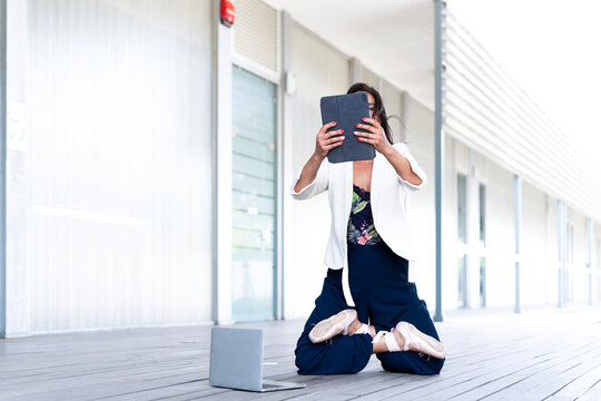Female balett dancer kneeling on the ground, using tablet