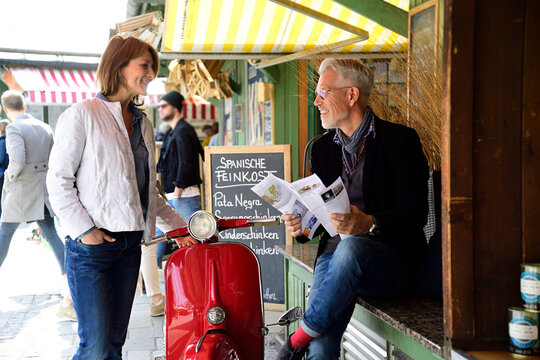 Mature couple meeting at the market, man raeding brochure