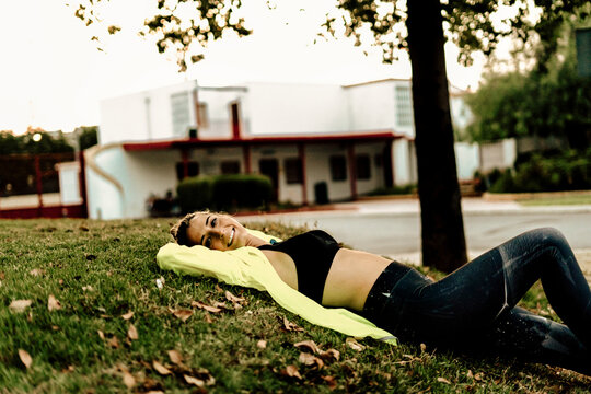 Sporty woman relaxing on grass after workout