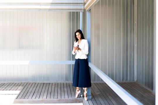 Female ballet dancer during training on a railing, using smartphone