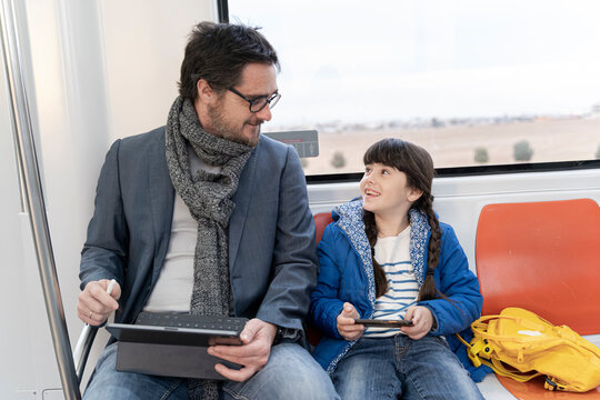 Father and daughter in metro and using tablet and smartphone