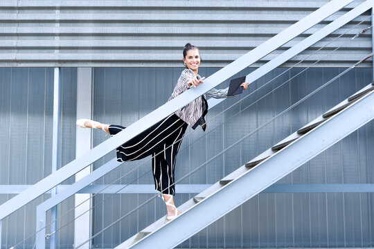 Female ballet dancer with smartphone and tablet standing on steps