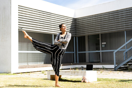 Female ballet dancer lifting her leg in front of an office building