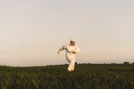 Man wearing protective suit and mask running in the countryside
