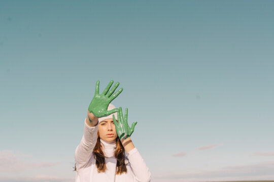 Young woman showing green painted palms