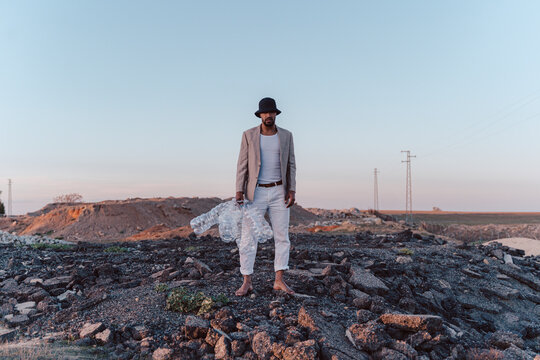 Young man holding empty plastic bottles in barren land