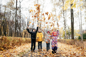 Group of four kids playing with autumn leaves