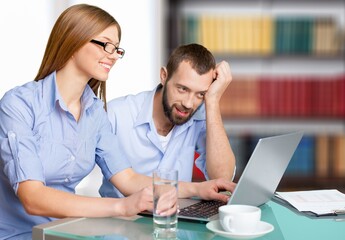 Obraz premium An attractive couple sit at a table in cozy room looking at laptop screen