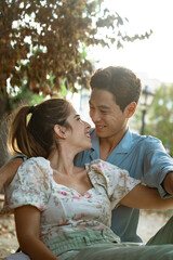 Naklejka premium Attractive portrait of young couple of asian man and european woman smiling at each other at the park during autumn