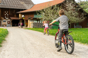 Girl and boy riding bicycle at a farm