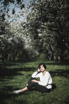 Woman sitting on meadow between apple trees
